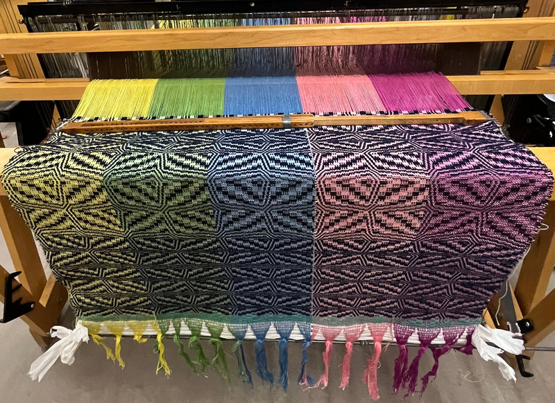 Woven fabric on a loom with colorful patterns in a workshop setting