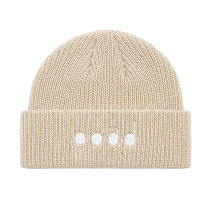 A beige ribbed knit beanie hat with a folded cuff, featuring three small white embroidered dots on the front.